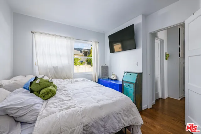 a bedroom with a bed wooden floor and flat screen tv