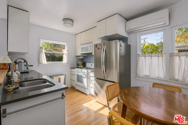 a kitchen with stainless steel appliances granite countertop a stove refrigerator and a dining table with wooden floor