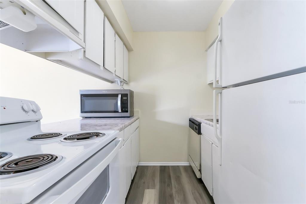 5317 Curry Ford Road, Unit J102 Orlando, FL 32812 - Photo 9 of 24 a kitchen with stainless steel appliances a white stove top oven and a refrigerator