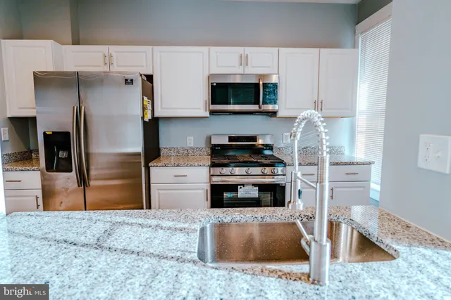 a kitchen with stainless steel appliances granite countertop a refrigerator a stove and a sink