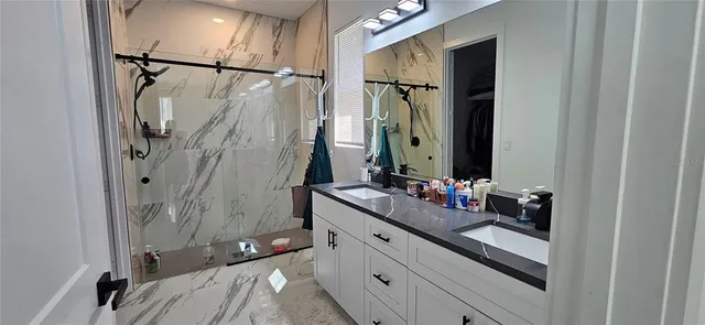 a bathroom with a double vanity sink mirror and shower