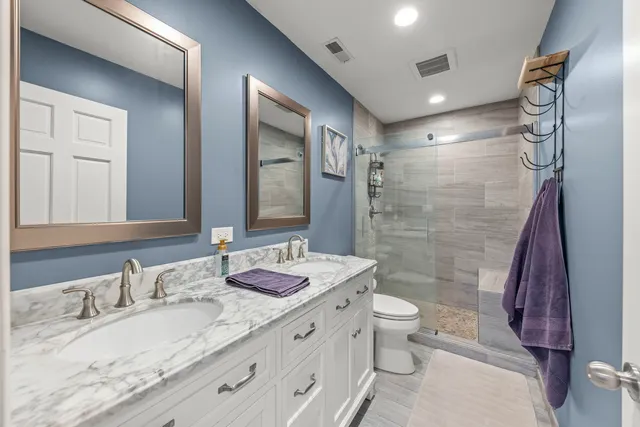 a bathroom with a granite countertop sink mirror vanity and toilet