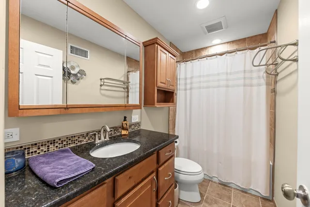 a bathroom with a granite countertop sink toilet and shower