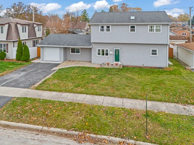 a view of a white house next to a yard and large trees