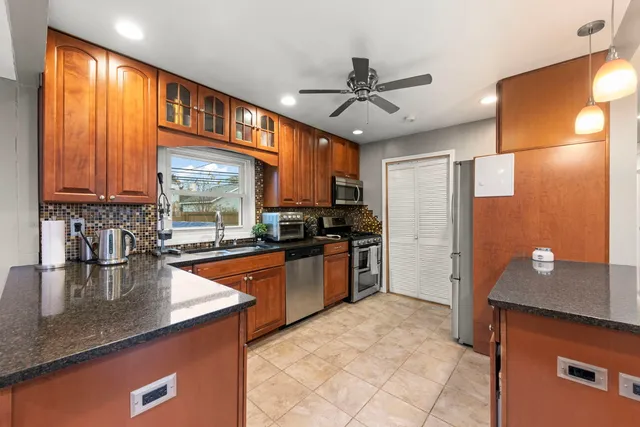 a kitchen with stainless steel appliances granite countertop a sink refrigerator and cabinets