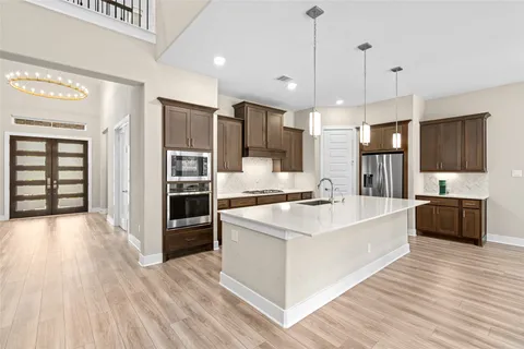 a large kitchen with stainless steel appliances a large counter top a stove a sink and a refrigerator