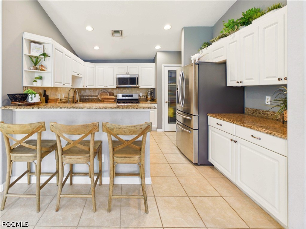 19694 Villa Rosa Loop Estero, FL 33967 - Photo 9 of 28 a kitchen with stainless steel appliances kitchen island granite countertop a refrigerator and microwave