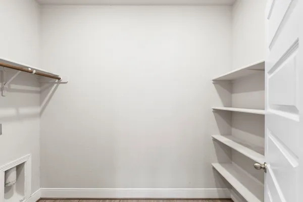 a large white kitchen with kitchen island a sink wooden floor and a refrigerator