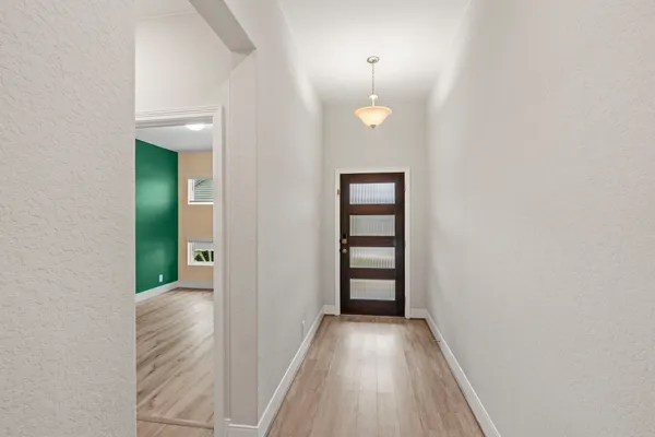 a view of an empty room with window and hardwood
