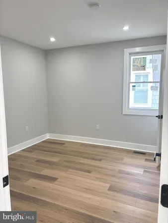 an empty room with wooden floor & closet area
