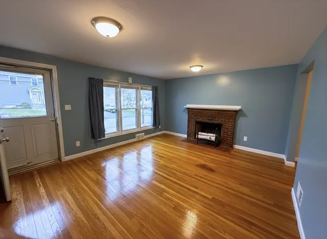 an empty room with wooden floor a fireplace and windows