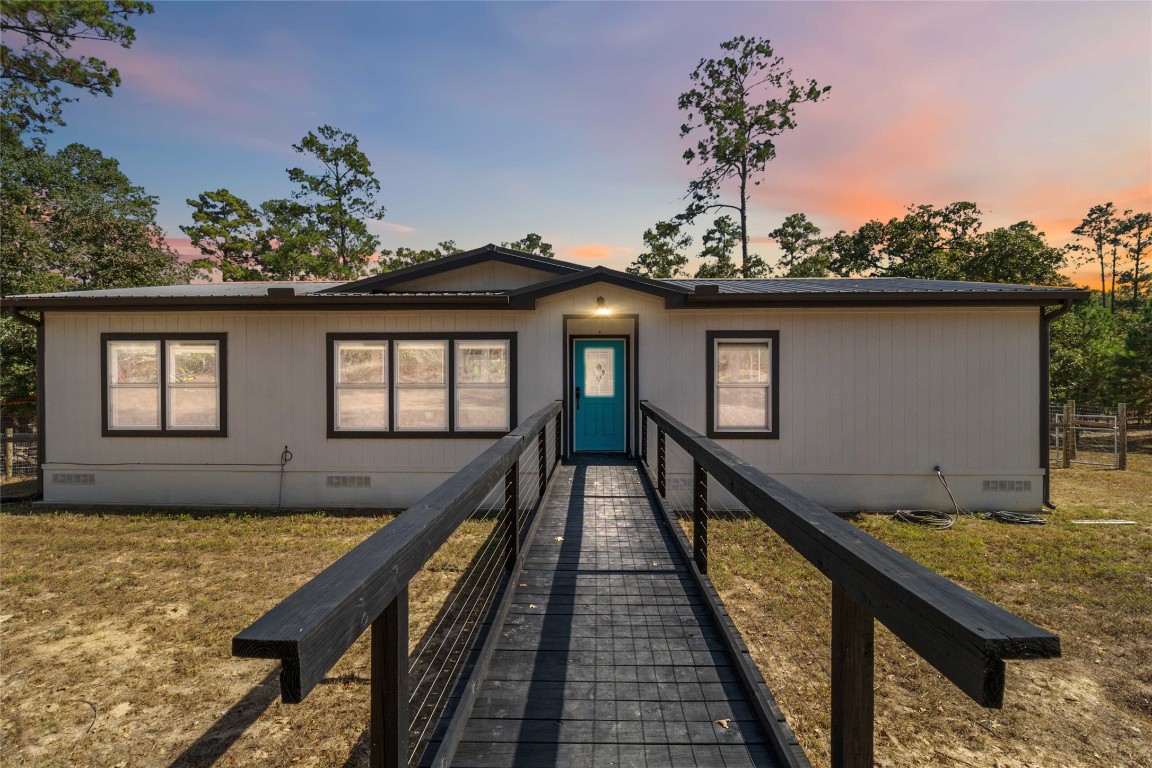 a view of a house with large windows and flower plants