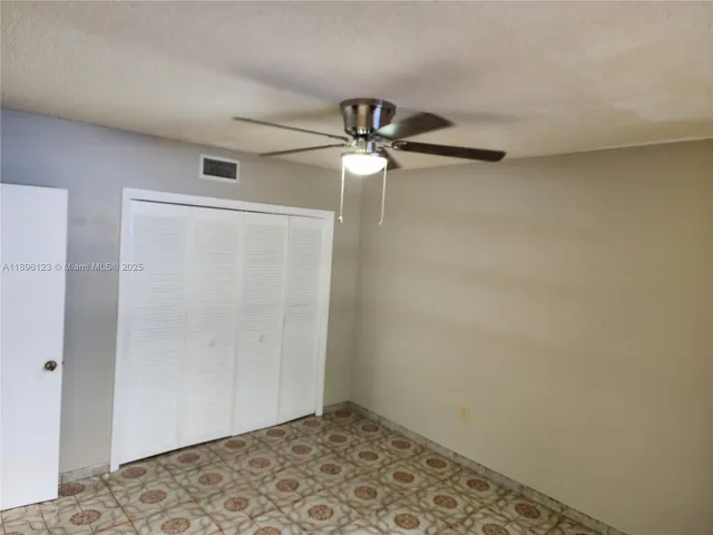 an empty room with a ceiling fan and a window