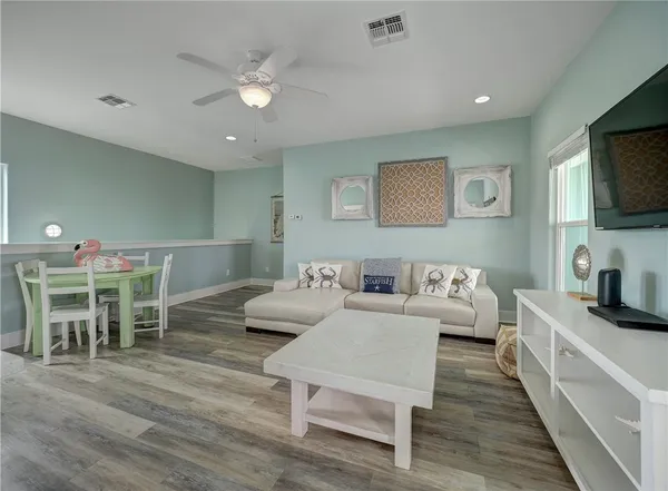 a living room with furniture a flat screen tv and kitchen view