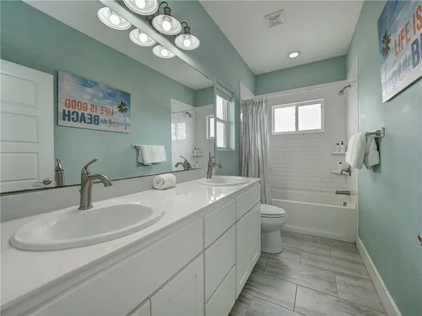 a bathroom with a double vanity sink a toilet and shower