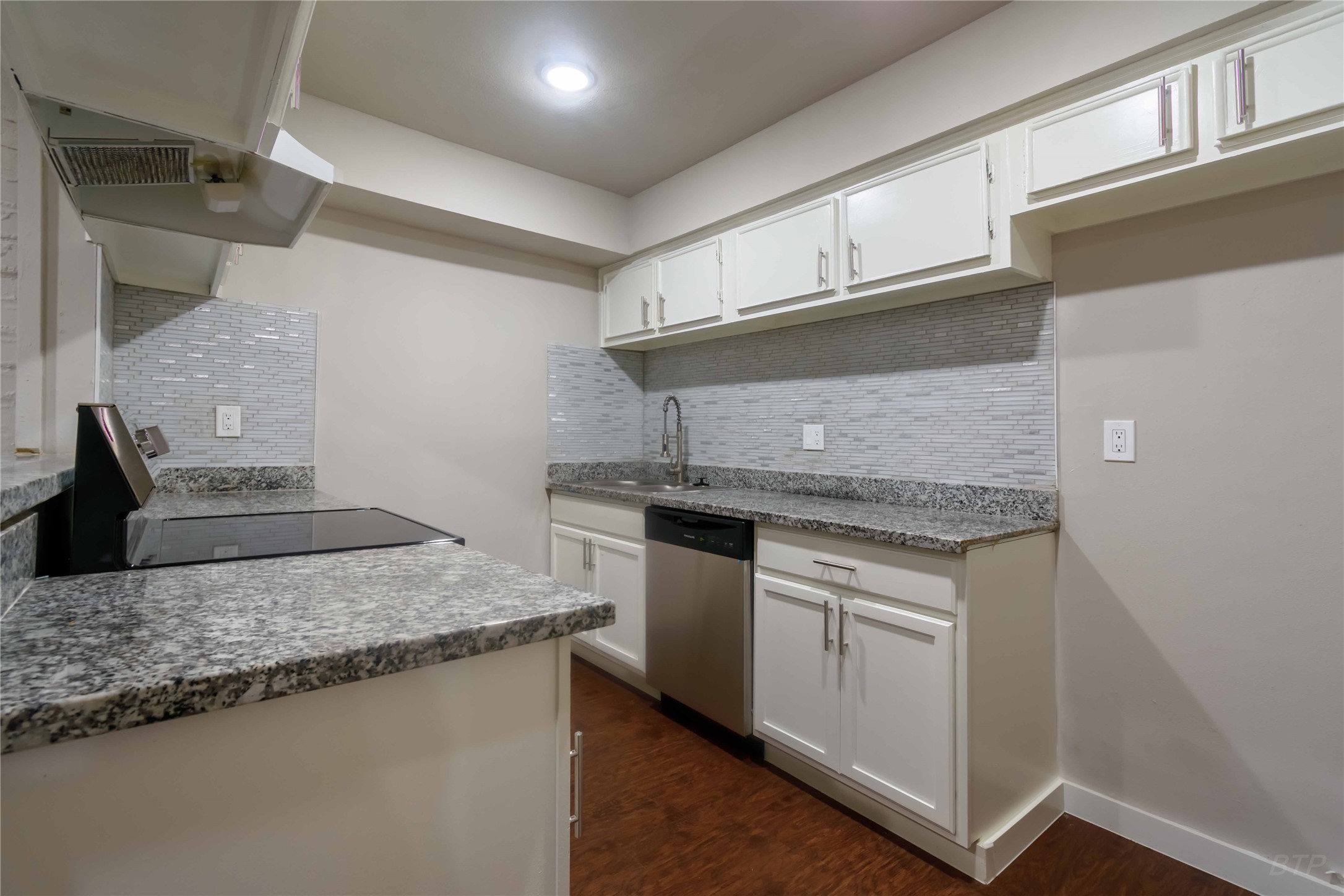 a kitchen with granite countertop a sink stove and cabinets