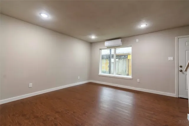 an empty room with wooden floor and a kitchen