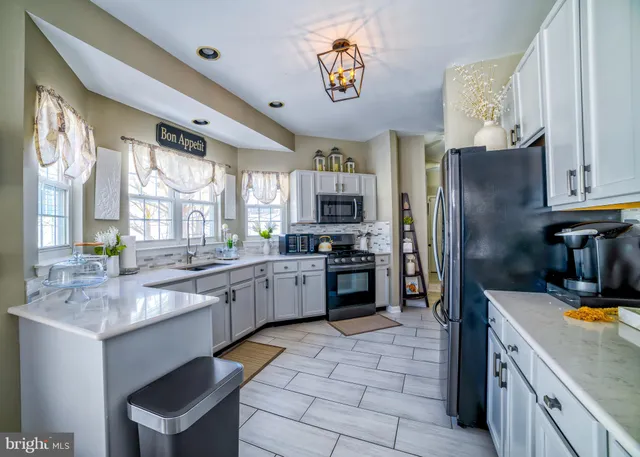 a kitchen with stainless steel appliances granite countertop a refrigerator a sink dishwasher a stove with wooden cabinets and floor