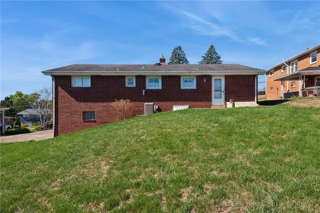 a view of a yard in front of a brick house with large windows