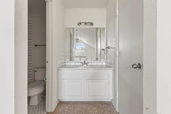 a bathroom with a granite countertop sink mirror and toilet