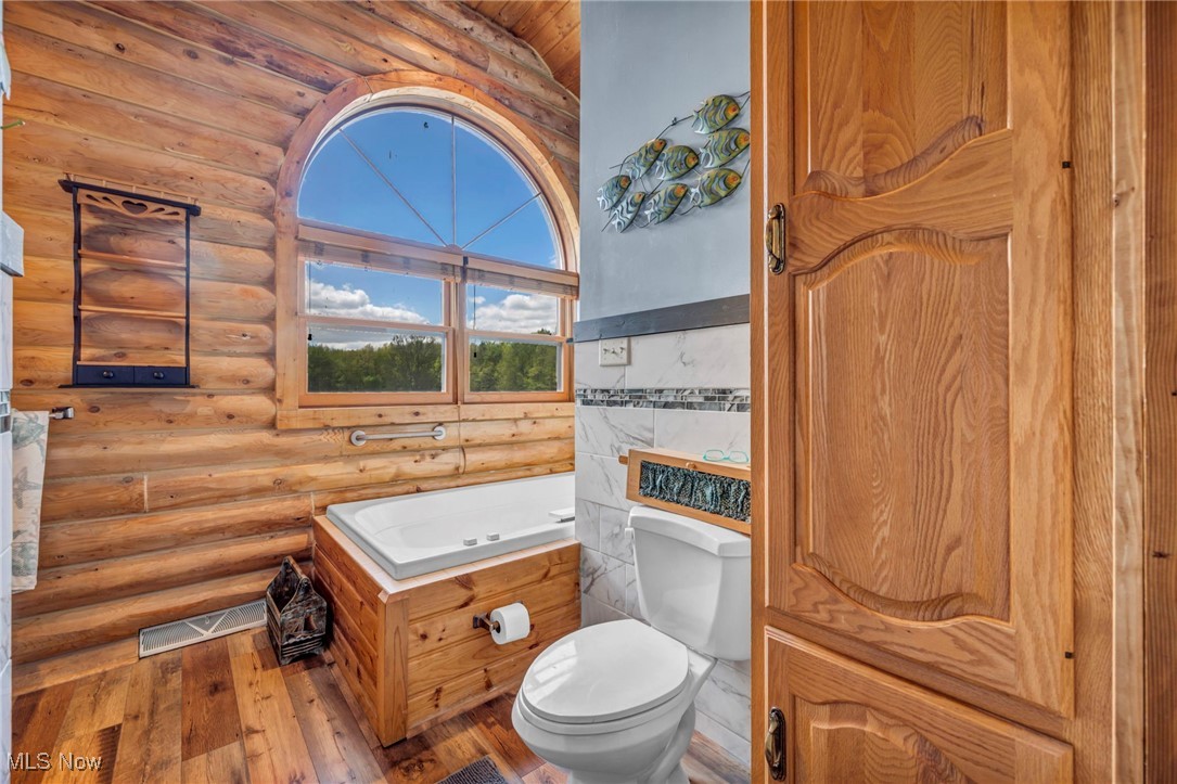 15180 Stoltz Road Diamond, OH 44412 - Photo 28 of 48 Bathroom with toilet, hardwood / wood-style floors, and rustic walls