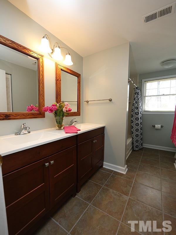 412 Southeast Maynard Road Cary, NC 27511 - Photo 15 of 19 Wonderful up-graded Hall Tub/Shower Bathroom with new cabinetry/double sinks, 12" tiled floor, dual flush high efficiency toilet and silver toned fixtures!