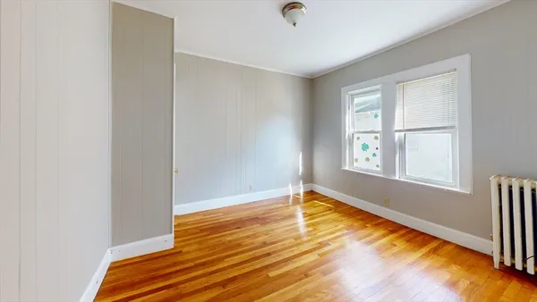 a view of empty room with wooden floor and fan