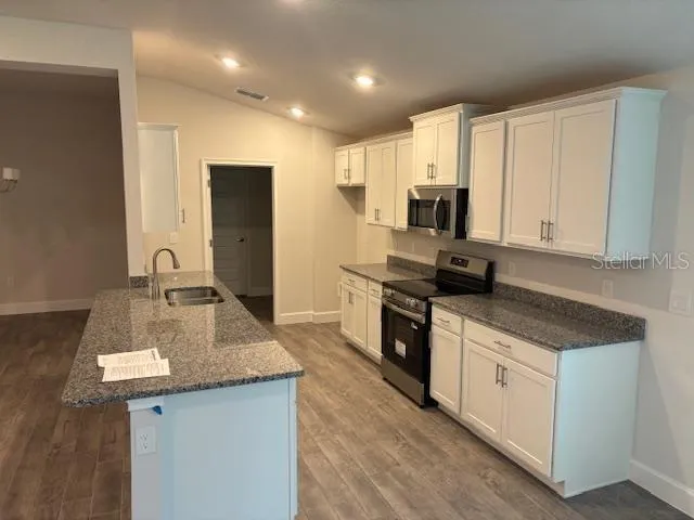 a kitchen with stainless steel appliances granite countertop a sink stove and refrigerator