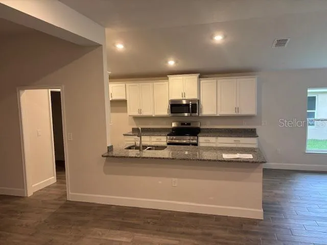 a view of kitchen with stainless steel appliances granite countertop white cabinets and refrigerator