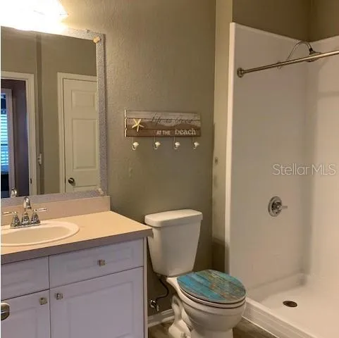 a bathroom with a sink a toilet a mirror and shower