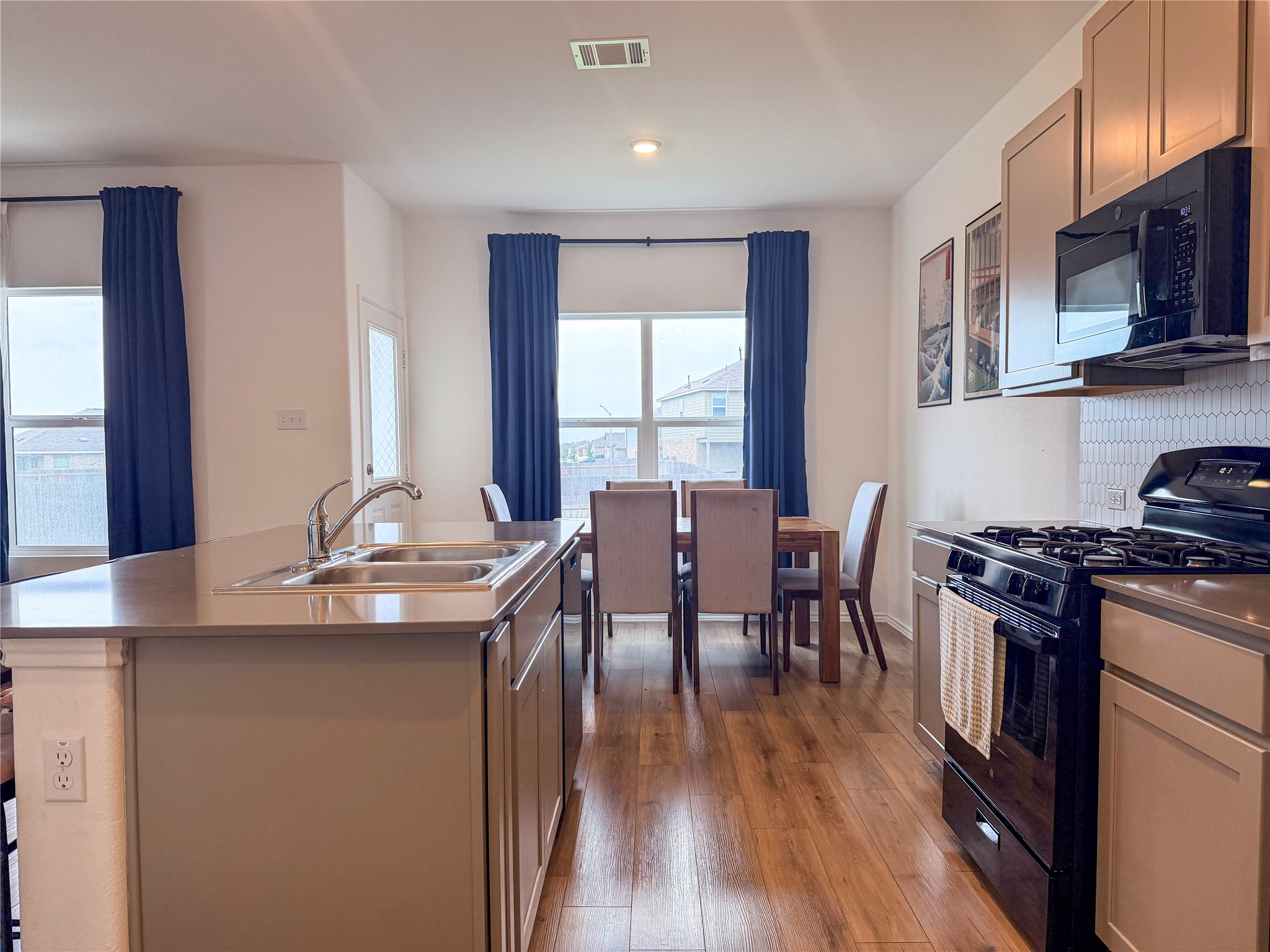 400 Canley Loop Hutto, TX 78634 - Photo 8 of 20 a kitchen with stainless steel appliances granite countertop a stove top oven a sink a dining table and chairs with wooden floor