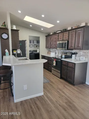 a large kitchen with stainless steel appliances a large counter top a sink a stove and a wooden floors