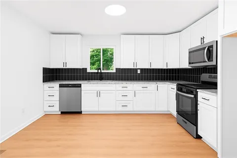 a kitchen with granite countertop a stove a sink and white cabinets