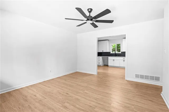 a view of a room with wooden floor a ceiling fan