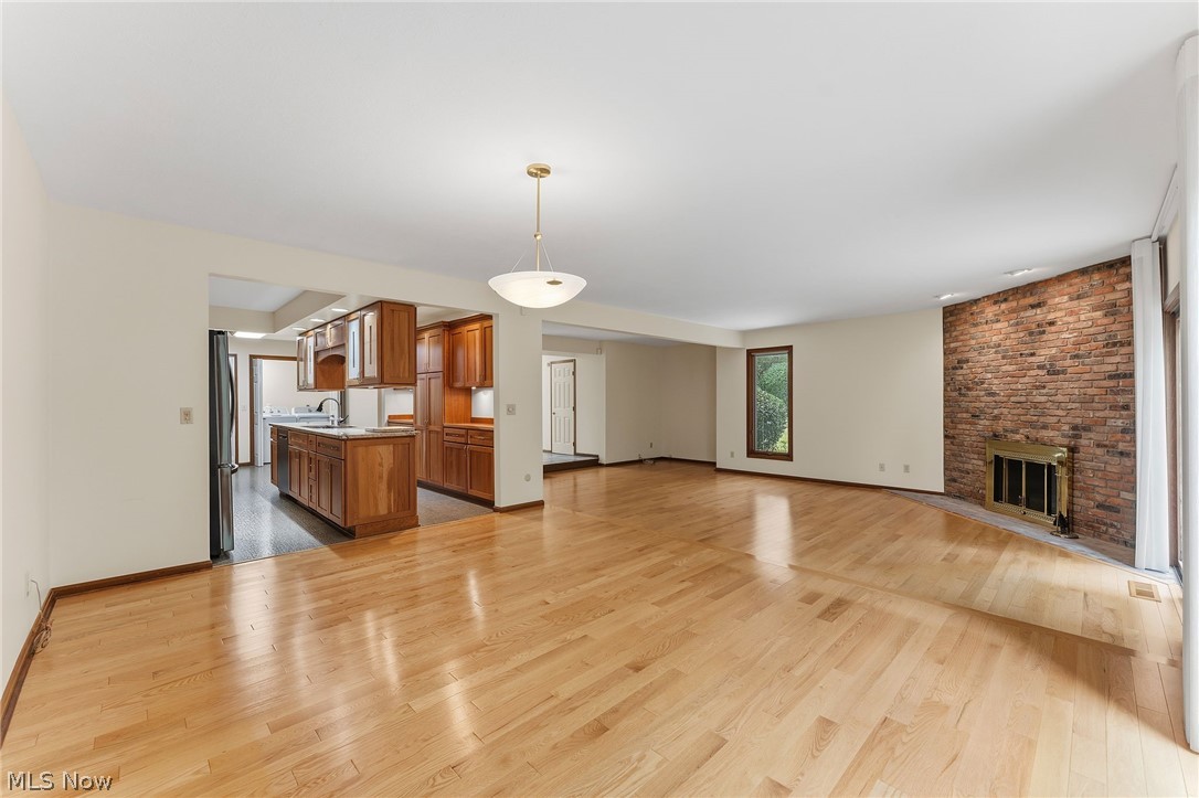 5741 Som Center Road, Unit 1 Solon, OH 44139 - Photo 16 of 50 Expansive living area with wood-finish flooring, brick fireplace surround with brass accents, and recessed wall paneling