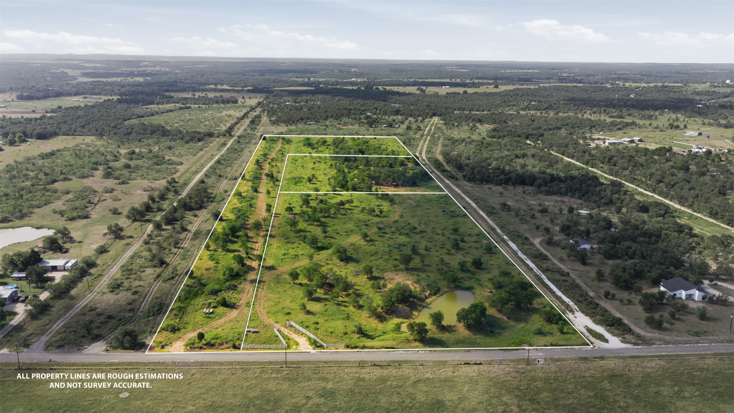 3280 County Road 466 Elgin, TX 78621 - Photo 7 of 13 Vast, verdant acreage with a tranquil pond awaits your vision for a serene estate.