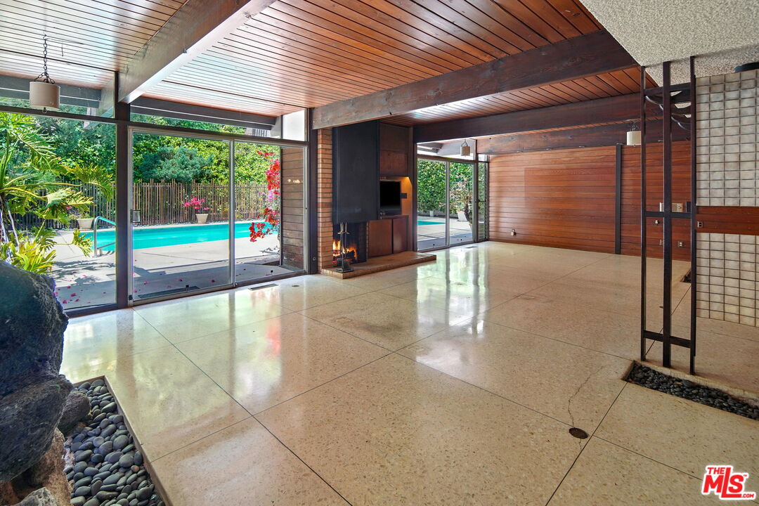 1335 Shadybrook Drive Beverly Hills, CA 90210 - Photo 10 of 39 a swimming pool with large glass windows and outdoor seating