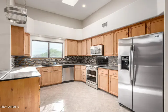 a kitchen with stainless steel appliances granite countertop a refrigerator a sink dishwasher a stove and white countertops with wooden floor