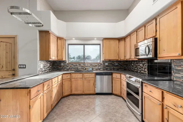 a large kitchen with stainless steel appliances granite countertop a stove a sink and a microwave