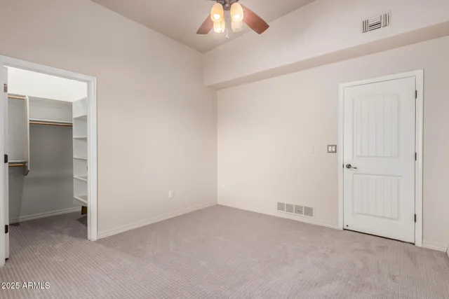 an empty room with a ceiling fan and closet area