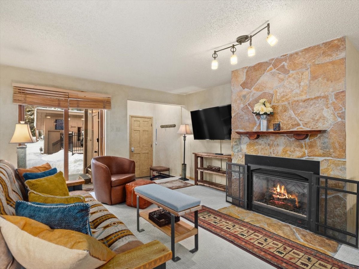 108 Guller Road, Unit B4 Frisco, CO 80443 - Photo 3 of 21 Living room with a fireplace, carpet, and a textured ceiling