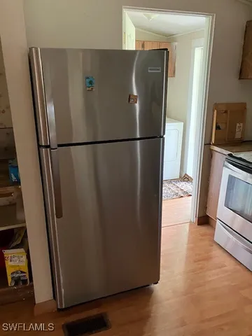 a view of a refrigerator in kitchen and an empty room