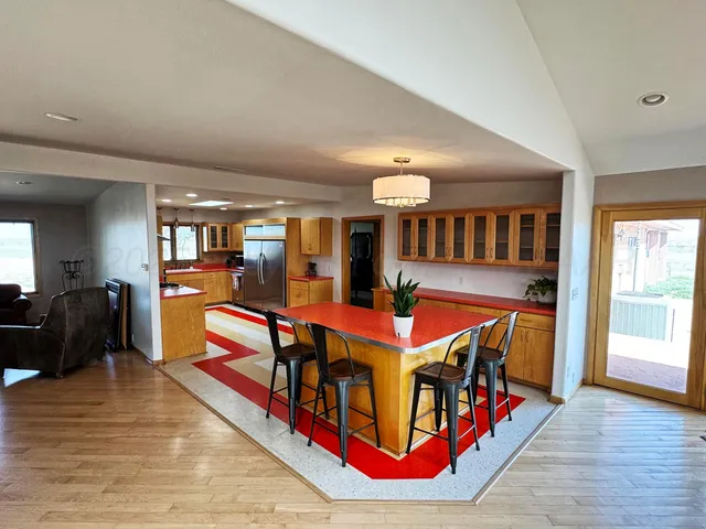 a living room with furniture a dining table wooden floor and a large window