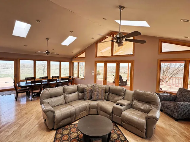 a living room with furniture a ceiling fan and a large window
