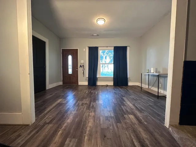 a view of a hallway with wooden floor and a living room