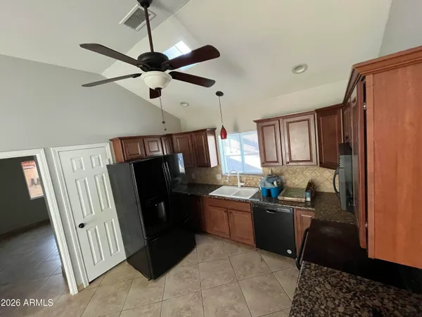 a kitchen with a sink a refrigerator wooden floor and a window