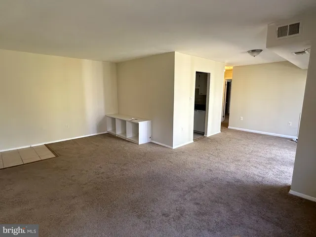 a view of an empty room with closet and a window