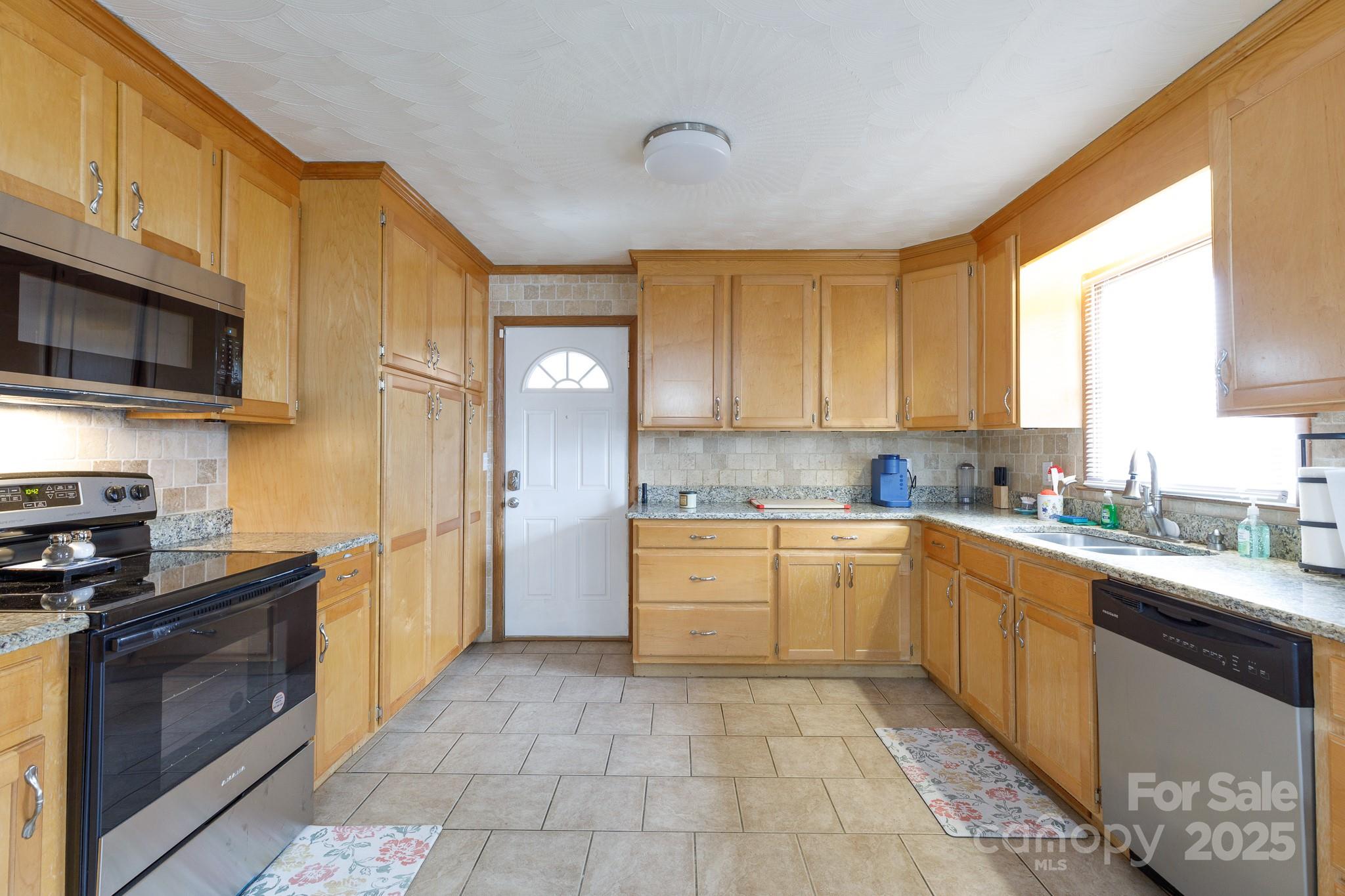 a kitchen with stainless steel appliances granite countertop a stove a sink and a microwave