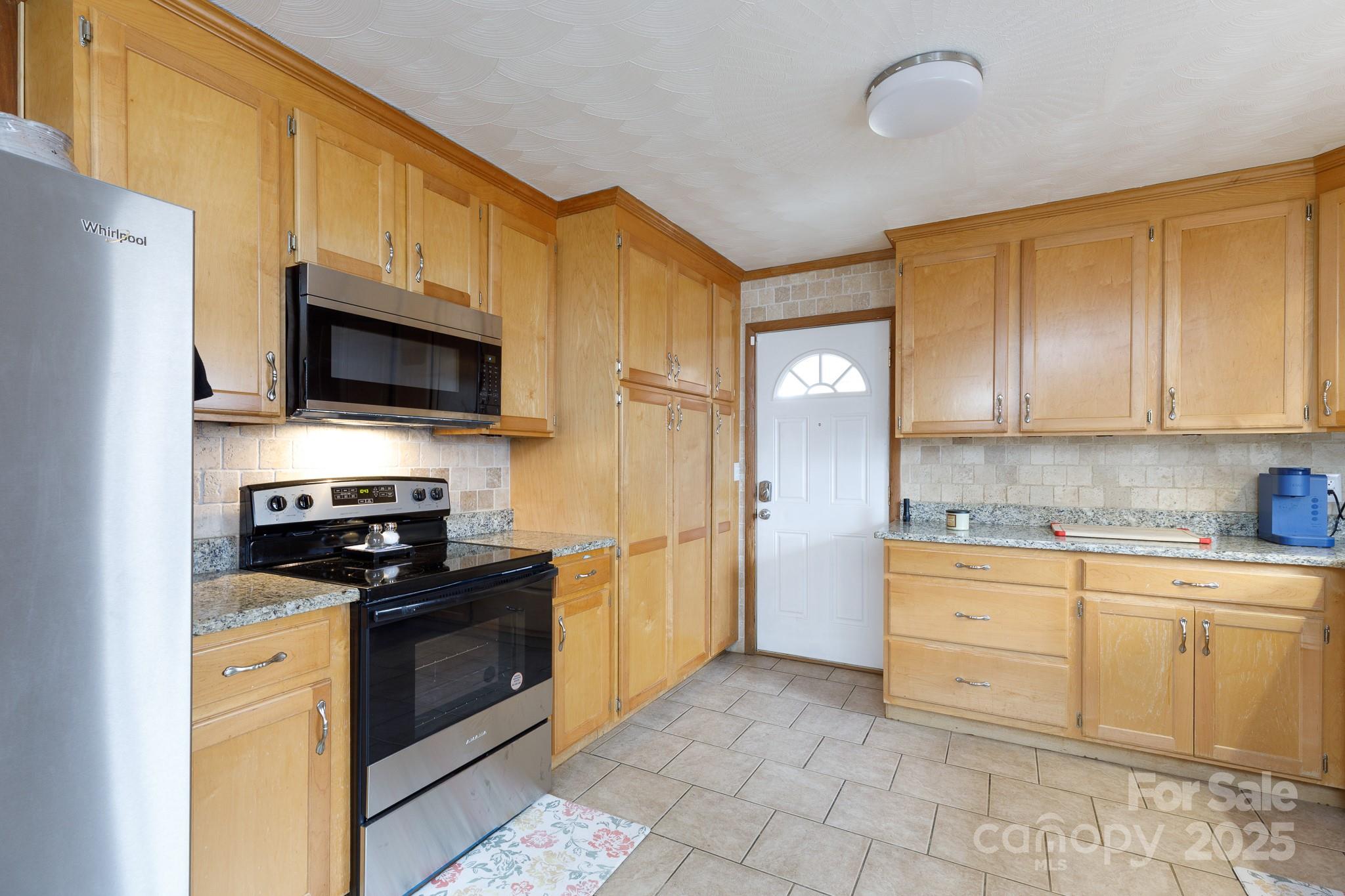 103 Perry Street Shelby, NC 28150 - Photo 4 of 22 a kitchen with stainless steel appliances granite countertop a stove top oven a sink dishwasher and a refrigerator with wooden cabinets