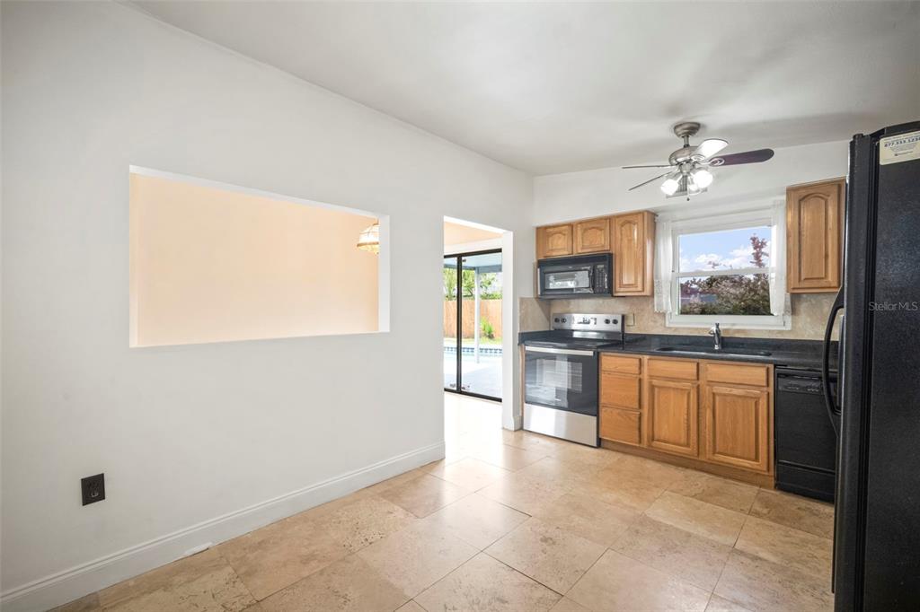 4712 Bessie Road Tampa, FL 33615 - Photo 19 of 28 a large kitchen with granite countertop a stove a sink dishwasher a refrigerator and a stove with wooden floor